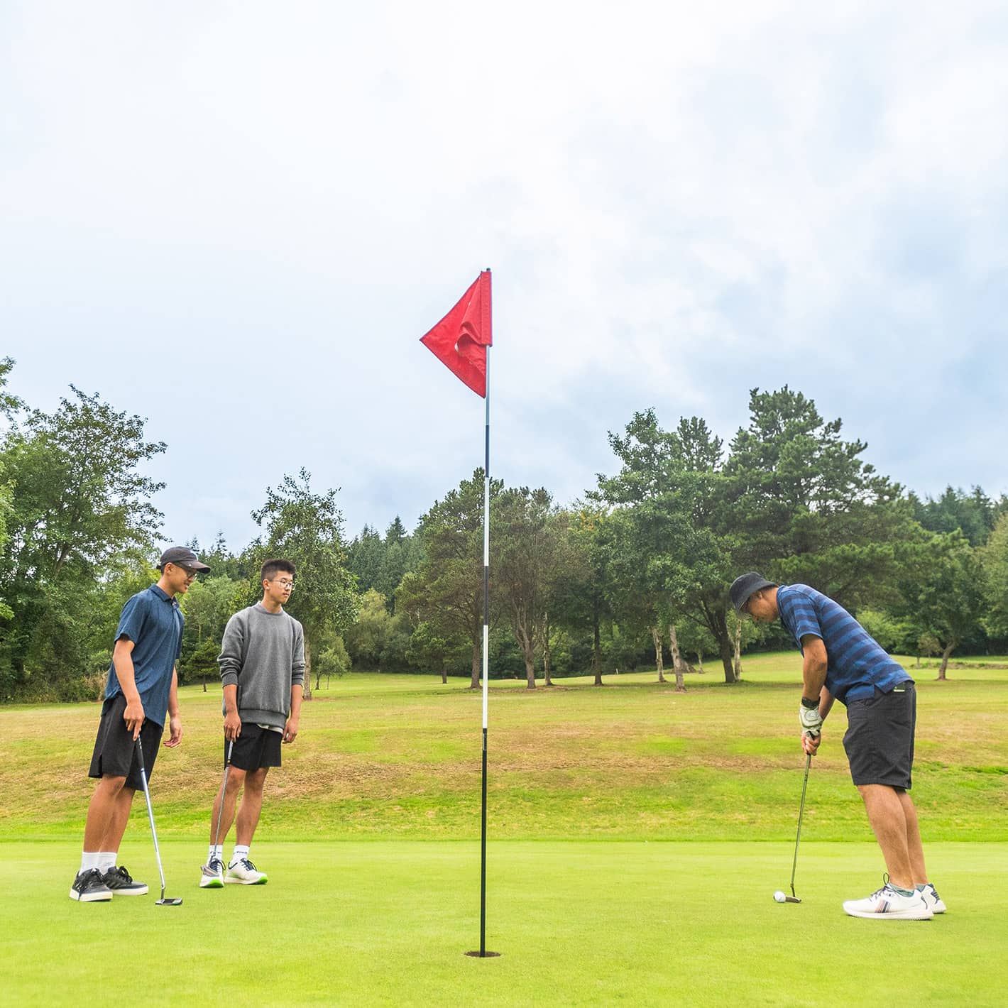 Three golfers on the green as one prepares to putt into the hole at Sidmouth Golf Club