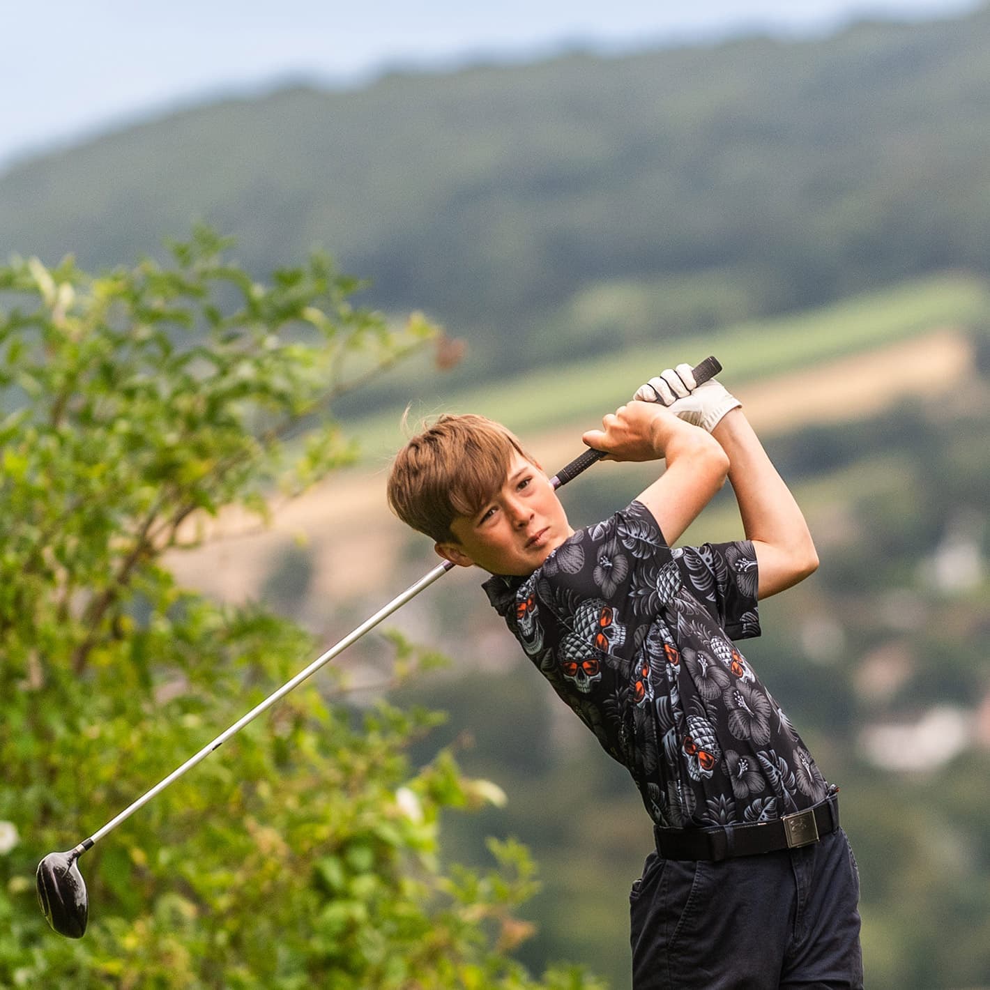 Junior golfer mid-swing after hitting the ball at Sidmouth Golf Club