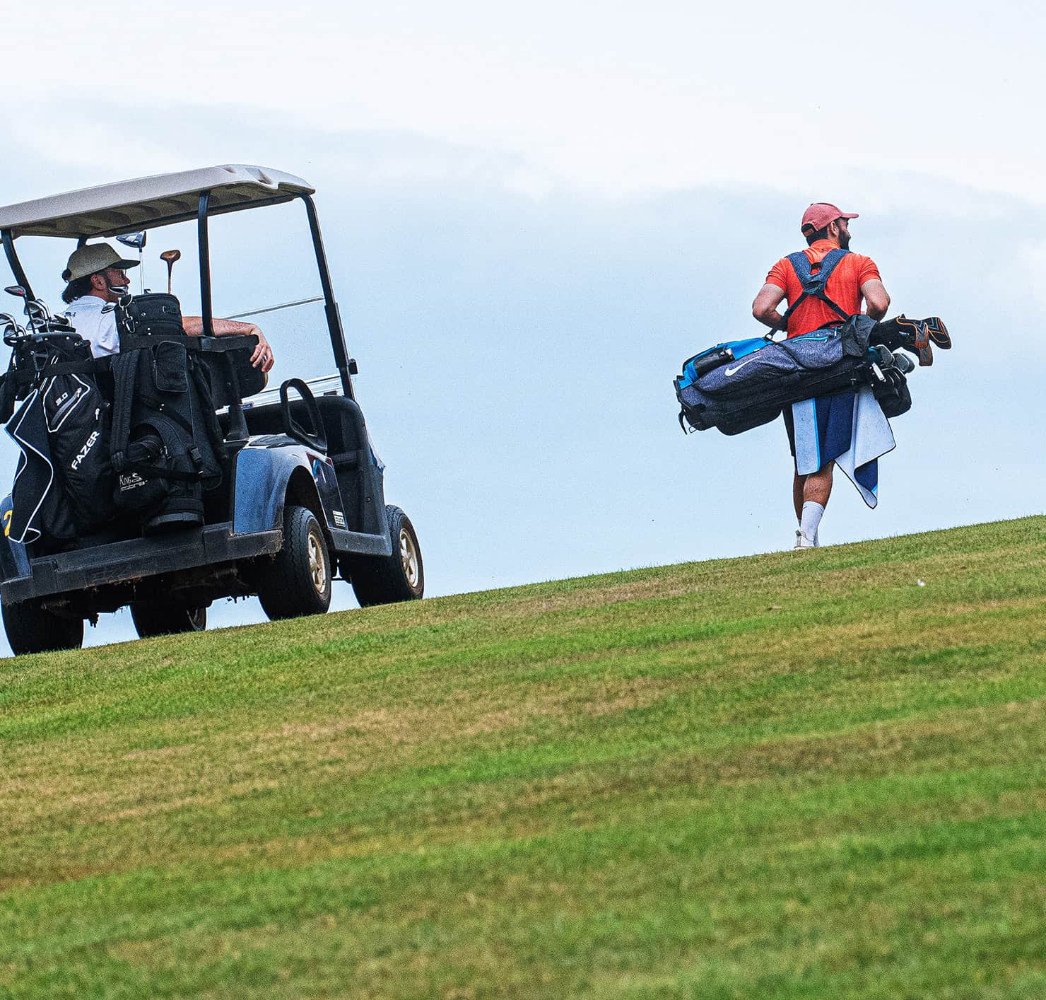 Golfer in a buggy and another carrying clubs overlooking the course at Sidmouth Golf Club